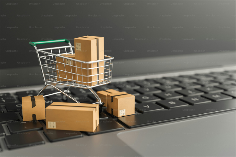 Online shopping concept with a cart and parcels on a laptop keyboard