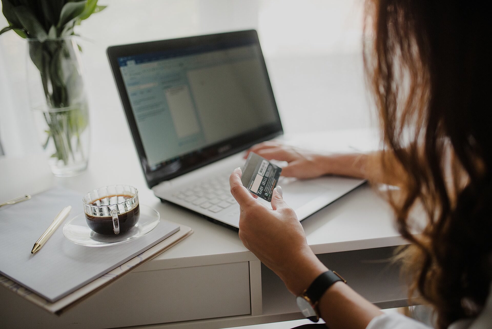 Buyer looking at a payment card while working on a laptop