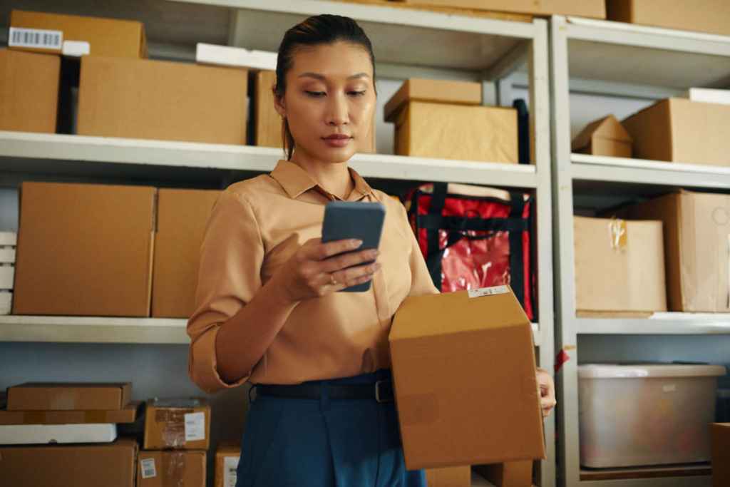Warehouse worker checking parcel details on a smartphone for an international order
