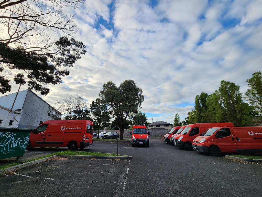 Australia Post delivery vans staged behind shops