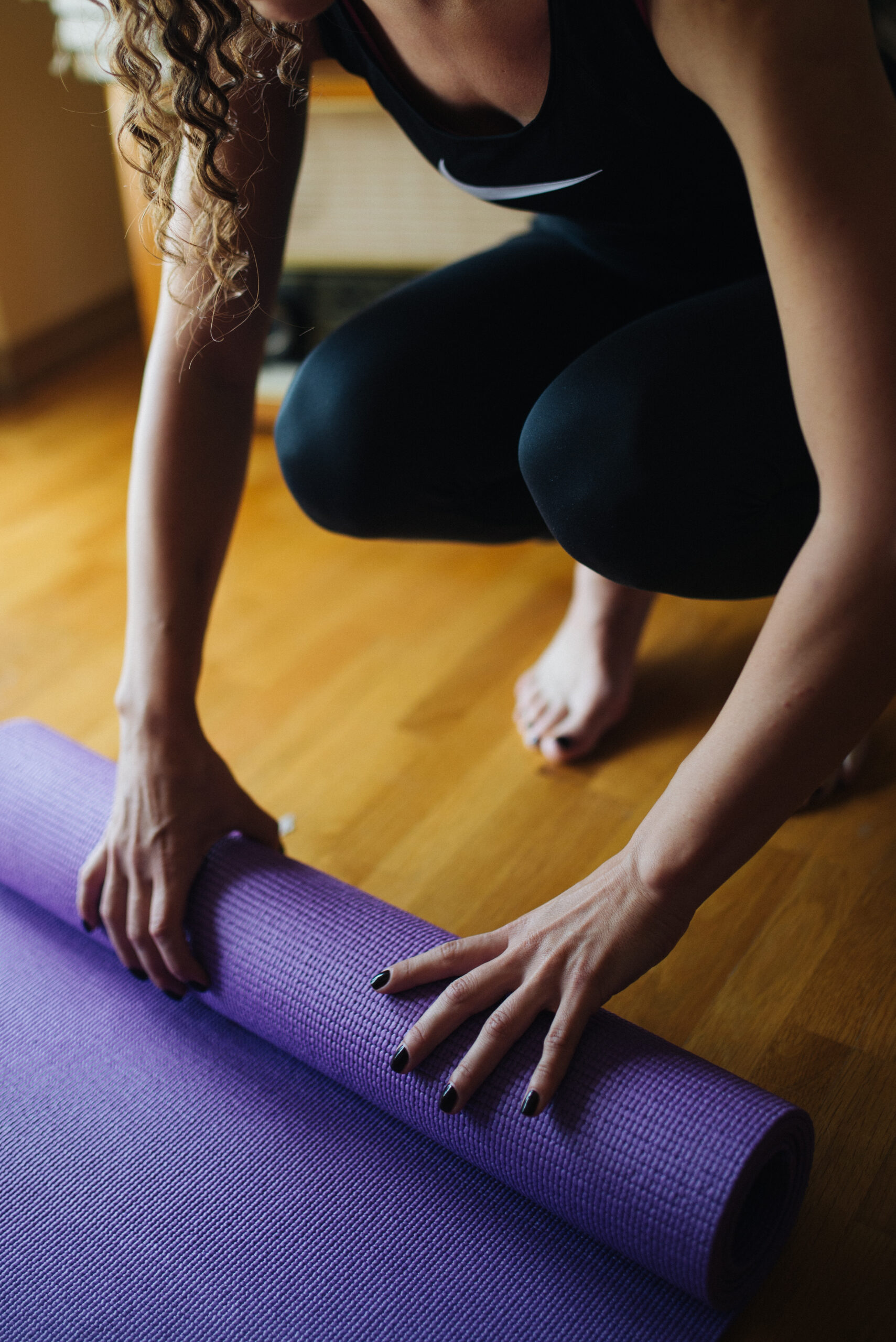 Person unrolling a yoga mat on the floor