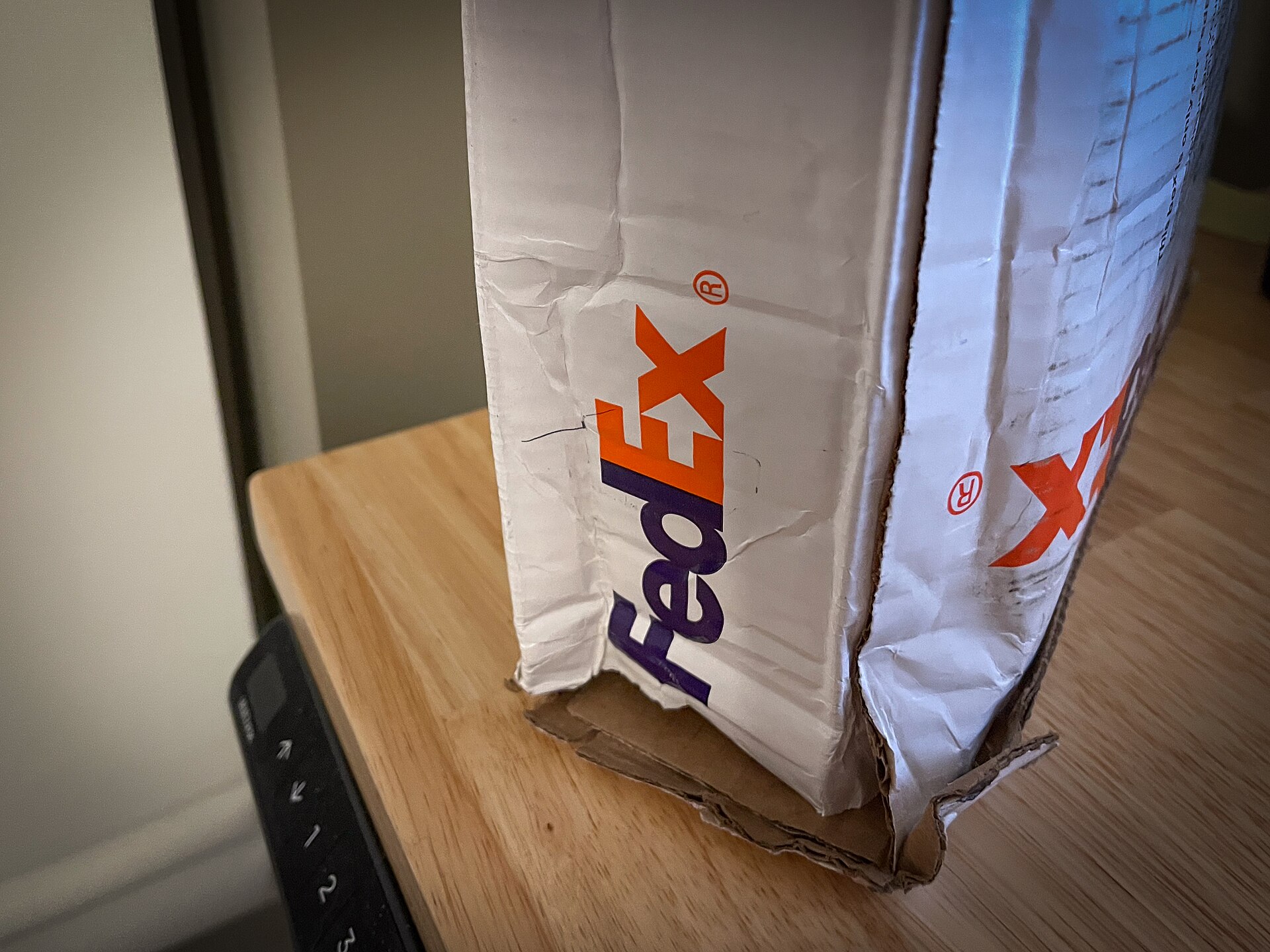 Damaged cardboard shipping box with crushed corner