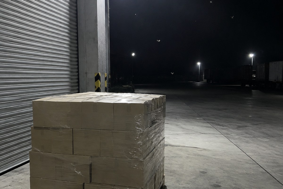 Wrapped cartons beside a warehouse loading door at night