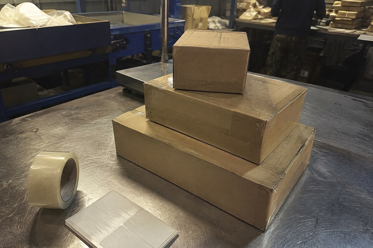 Cardboard parcels stacked on a workbench beside blue warehouse equipment